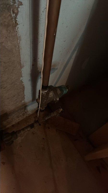 Completed plumbing maintenance visit to address valve replacement in basement utility area. Removed deteriorated brass shutoff valve showing significant corrosion and patina buildup, as evidenced by turquoise-green copper oxidation residue on floor surface. Installed new valve assembly with proper copper pipe connections to restore water control functionality to the system.