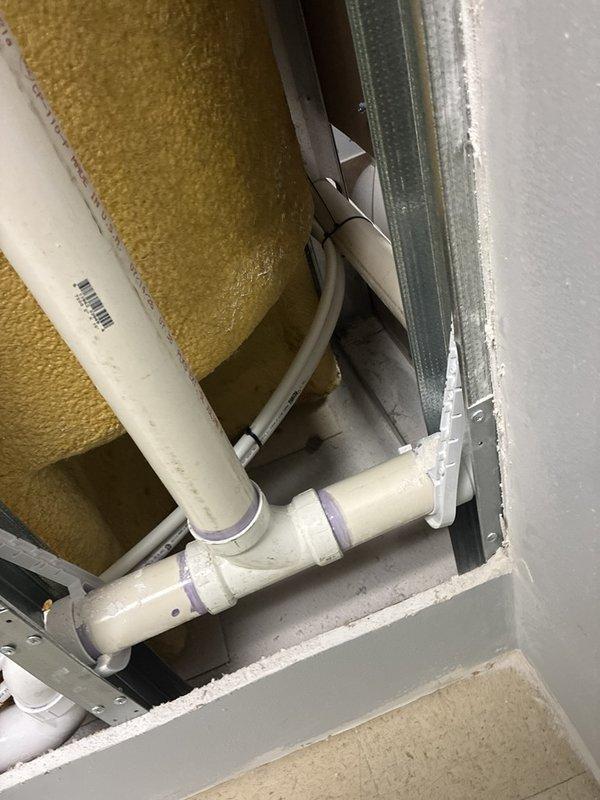 Installed a new 2" PVC drain line by tying into an existing 2" stack located in the cavity between the men's and women's restrooms, routing the drain line through the wall to a new washing machine location in the accessible restroom stall. Ran PEX water supply lines from the water heater room to the new laundry box location, installing shut-off valves at the water heater connections with red and blue valve handles. Removed necessary sheetrock sections to access stud cavities for pipe routing, installed the laundry box with venting extended into the attic space, and secured all piping with stud guards and mounting brackets to protect against future damage. Pressure tested all connections for leaks, verified proper drainage, and cleaned the work area of all construction debris upon completion.