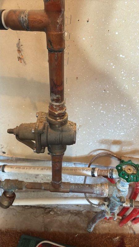 # Plumbing Maintenance Visit Completed

Performed preventive plumbing maintenance inspection on residential property. Inspected accessible plumbing infrastructure including copper supply lines, shut-off valves, and T-junction fittings in utility area. Noted advanced corrosion and oxidation on vertical copper piping and central valve assembly, with visible rust patina, mineral deposits, and scale buildup throughout system. Documented condition of plumbing components showing significant age-related deterioration. Checked under-cabinet areas and accessible pipe runs for leaks or immediate concerns. Photographed corroded valve mechanisms and copper pipe assemblies for maintenance records. System remains operational with no active leaks identified during inspection.