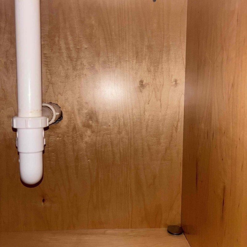 Installed two shut-off valves under lavatory sink by cutting access into cabinet wall to reach water supply lines. Building water supply was shut down to facilitate cutting into existing lines and installing isolation valves for the faucet. Following valve installation, faucet cartridges were removed and replaced with new cartridges supplied by property owner, restoring proper operation to the fixture.