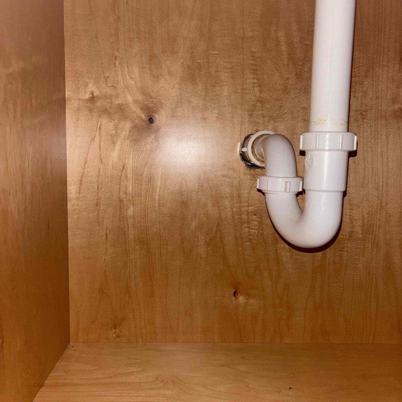 Installed two shut-off valves under lavatory sink by cutting access into cabinet wall to reach water supply lines. Building water supply was shut down to facilitate cutting into existing lines and installing isolation valves for the faucet. Following valve installation, faucet cartridges were removed and replaced with new cartridges supplied by property owner, restoring proper operation to the fixture.