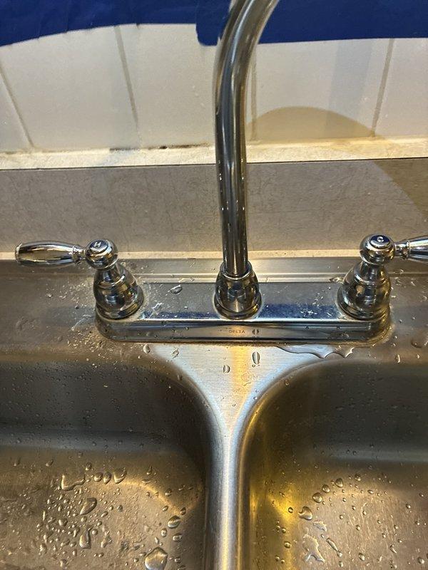 Replaced hot and cold shut-off valves for kitchen sink faucet installation. Removed old brass valves showing signs of corrosion and water staining, installed new quarter-turn shut-off valves, and reconnected braided stainless steel supply lines to ensure proper water flow and temperature control to the chrome kitchen faucet with dual handles.