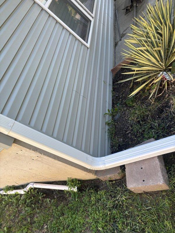Responded to reported leak with unknown source location. Conducted thorough exterior inspection of residential property, examining roof penetrations, plumbing vents, gutter system, and ground-level drainage components. Located and documented potential water intrusion points including roof stack penetrations and exterior PVC drainage discharge at foundation level for customer awareness and future repair planning.