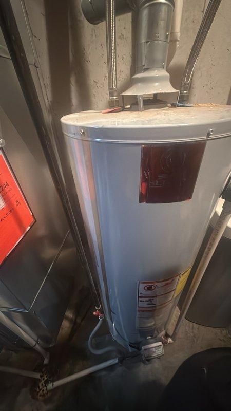 Responded to service call for leaking water heater in basement. Upon arrival, inspected residential water heater unit and surrounding plumbing connections, including copper supply lines and PVC drainage system. Identified source of leak, performed necessary repairs to stop water discharge, and verified proper operation of unit. Documented existing conditions with photographs showing water heater installation, associated ductwork, and plumbing configuration for service records.