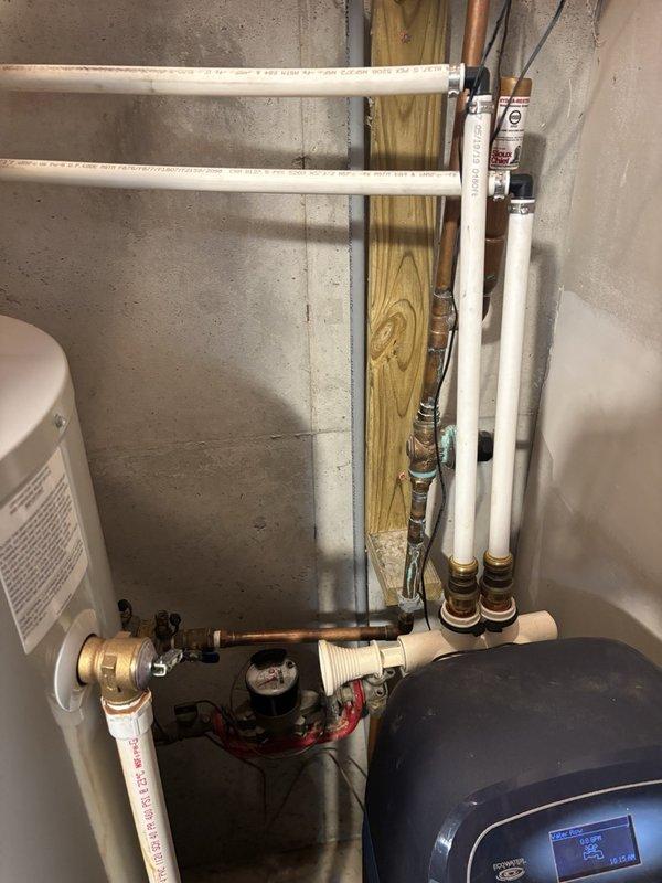Completed plumbing maintenance inspection and pressure testing at residential property. Verified proper operation of water heater, distribution piping, pressure tank system in basement utility area, and tested exterior hose bib with pressure gauge reading to ensure adequate water pressure throughout the system.