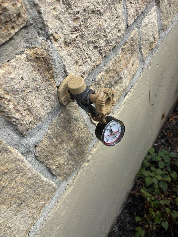 Completed plumbing maintenance inspection and pressure testing at residential property. Verified proper operation of water heater, distribution piping, pressure tank system in basement utility area, and tested exterior hose bib with pressure gauge reading to ensure adequate water pressure throughout the system.
