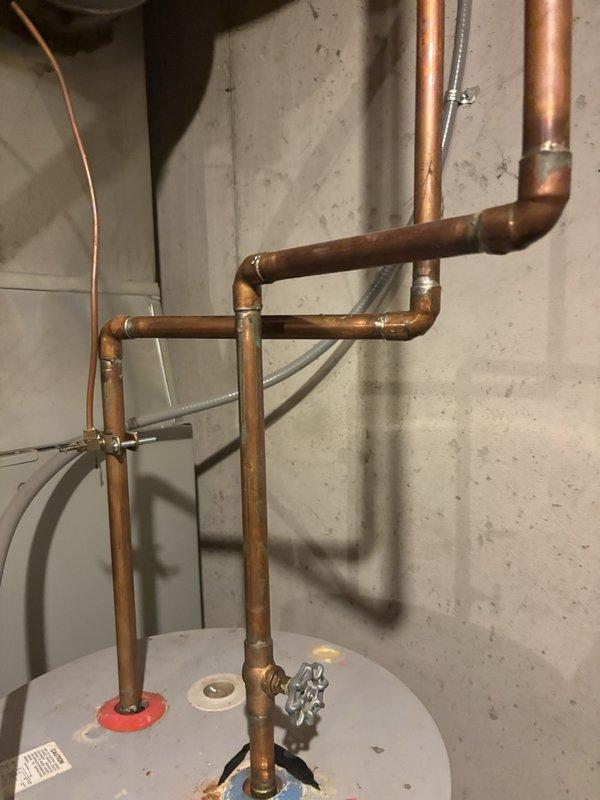 Performed routine plumbing maintenance inspection on residential water heater installation. Documented copper piping configuration, shutoff valves, and connections to verify proper installation and system integrity. All components including pipe joints, flexible conduit, and tank connections were photographed and found to be in satisfactory operating condition.