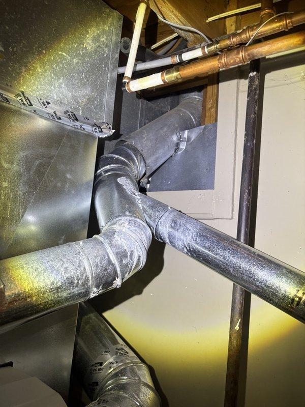 Responded to service call for reported water heater leak and rust concerns on gas-fired unit in basement. Upon arrival, conducted thorough inspection of water heater and surrounding plumbing infrastructure. Examination revealed no active leaking from the water heater tank itself. Observed frost accumulation on overhead wooden beams near plumbing runs, indicating potential condensation issues in the utility space. Inspected all visible copper piping, PEX connections, and brass fittings for signs of moisture or corrosion. Verified gas water heater connections and venting system integrity. Documented existing conditions with photographs showing plumbing infrastructure, HVAC ductwork, and utility space configuration. Advised customer that observed frost buildup may be contributing to moisture concerns rather than water heater failure. Unit operational at time of inspection with no immediate safety concerns identified.