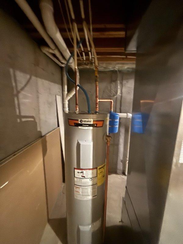 Completed installation of a 40-gallon electric water heater with thermal expansion tank in basement utility area. Installed unit in confined space between walls with proper clearances maintained for ventilation and service access. Connected copper supply lines to tank inlet and outlet ports, installed thermal expansion tank on cold water supply line to protect against thermal expansion pressure buildup in closed plumbing systems. Routed piping vertically to existing distribution lines at ceiling joists, applied blue foam pipe insulation to hot and cold water lines to minimize heat loss and prevent condensation. Verified all electrical connections to unit specifications, tested temperature and pressure relief valve operation, and confirmed proper grounding. System tested and operational upon completion.