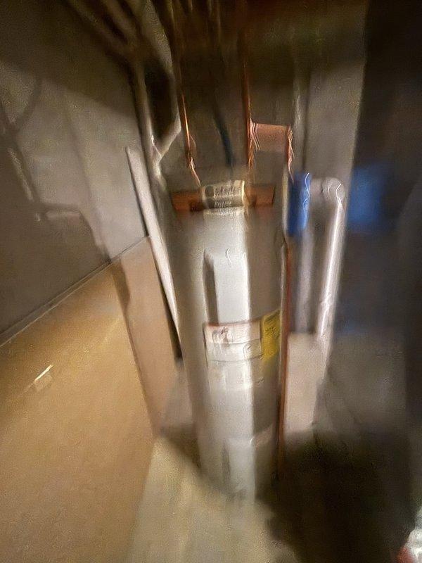Completed installation of a 40-gallon electric water heater with thermal expansion tank in basement utility area. Installed unit in confined space between walls with proper clearances maintained for ventilation and service access. Connected copper supply lines to tank inlet and outlet ports, installed thermal expansion tank on cold water supply line to protect against thermal expansion pressure buildup in closed plumbing systems. Routed piping vertically to existing distribution lines at ceiling joists, applied blue foam pipe insulation to hot and cold water lines to minimize heat loss and prevent condensation. Verified all electrical connections to unit specifications, tested temperature and pressure relief valve operation, and confirmed proper grounding. System tested and operational upon completion.
