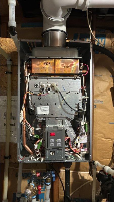 Responded to intermittent E10/E12 error codes on a wall-mounted tankless water heater. Removed the front cover and inspected the heat exchanger, flue and vent connections, ignition and flame rod terminals, wiring harness, and control board. Found heat discoloration on the copper heat exchanger and no visible frost, rust, or physical damage. Verified wiring and terminal connections and confirmed the vent and combustion air pathways were intact.