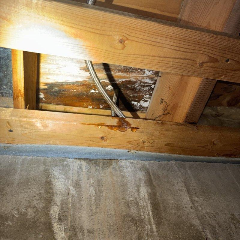 Located and repaired a leaking refrigerator water supply line that was allowing water to migrate through the floor into the basement below. Isolated the line at the shutoff valve, replaced the failed supply tubing and push-fit connections, then pressure-tested the system to confirm there were no leaks. Water-stained flooring, baseboard, and floor joist areas were documented, and the affected materials were noted for drying and further evaluation.