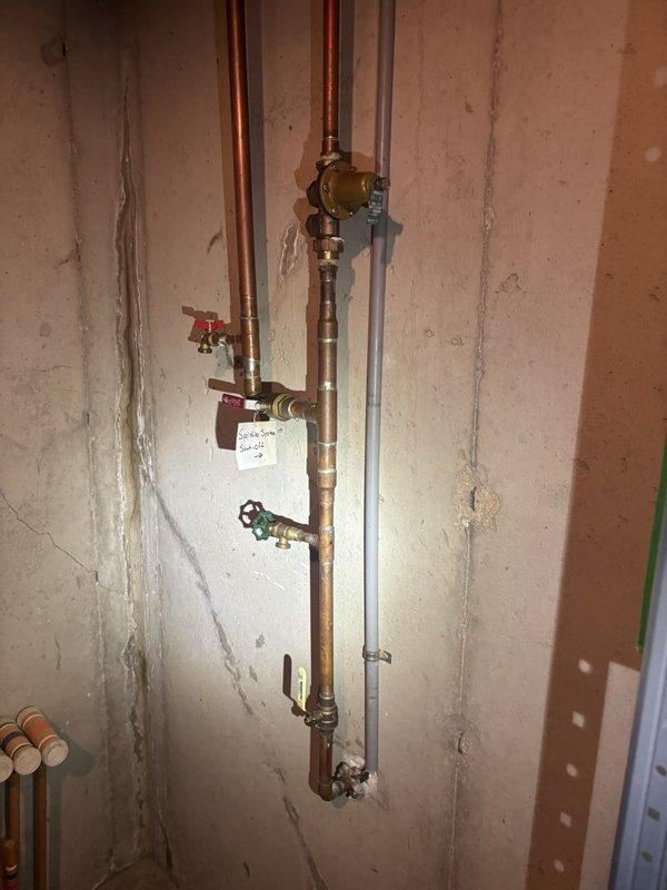 Performed a scheduled plumbing maintenance visit including a tankless water heater flush to remove mineral scale and sediment from the heat exchanger and restore efficient operation. Verified water pressure at the exterior hose bib using a pressure gauge, with readings within the normal 50–60 psi range, and inspected the copper supply piping, pressure regulator, and isolation valves at the main utility area, finding all components in serviceable condition.