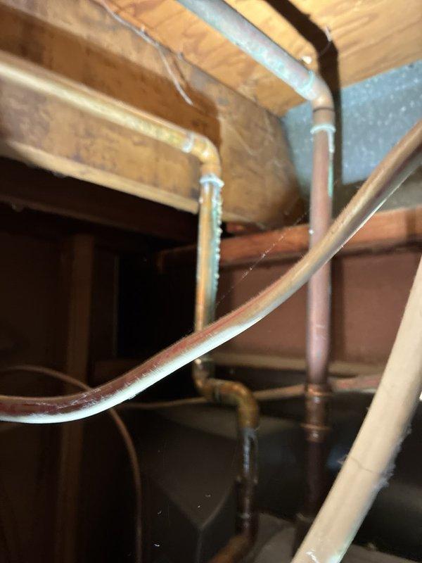 Inspected the toilet tank assembly, including the fill valve, overflow tube, flush valve, and flush lever, and serviced the components to restore proper operation. Also inspected the exposed copper supply lines in the crawl space, noting oxidation and mineral buildup at the soldered joints and elbow fittings for future monitoring.