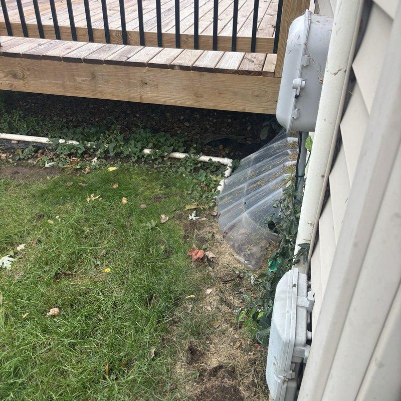 Responded to an existing submersible sump pump that was cycling on but discharging water out of the system onto the carpet. Pulled back the carpet and padding to expose the sump pit and inspected the pump, PVC discharge piping, check valve, rubber coupling, and power connection to identify the source of the leak. Also inspected the exterior discharge line and surrounding grade to verify proper drainage away from the foundation.