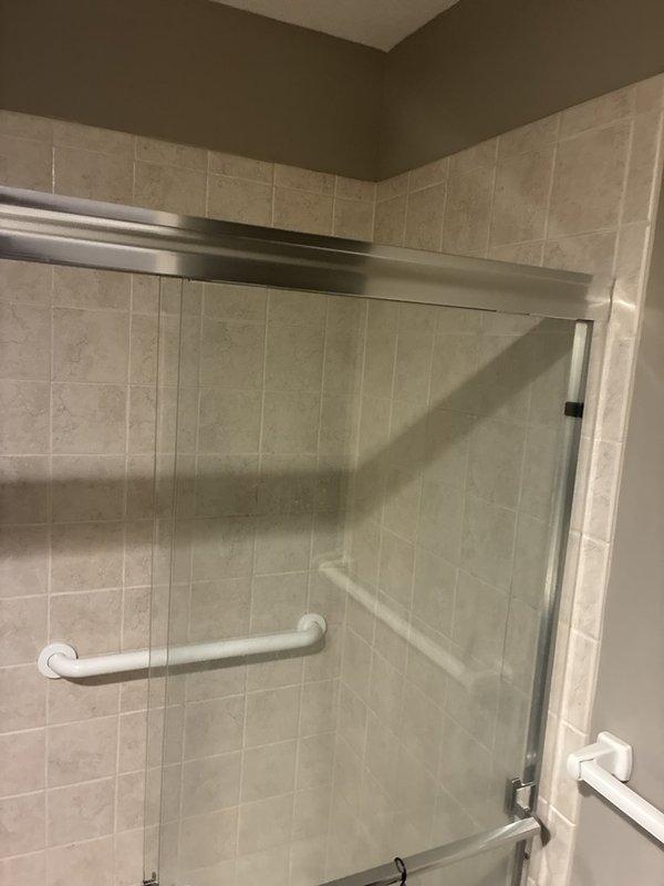Reinstalled and secured the previously removed sliding glass shower door panels and side panels, seating the door hangers in the top track and verifying all fasteners were tight. Confirmed smooth roller operation, proper alignment, and a stable, safe enclosure with no visible damage to the glass, frame, or tile.