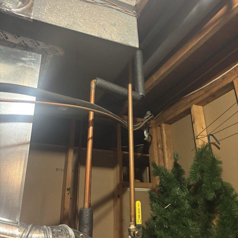 Performed a inspection of the gas tanked water heater, including the supply and distribution piping, shutoff valves, and surrounding ductwork, with no active leaks, frost, or significant damage found. Noted corrosion at a copper branch joint and a drain/hose-bib valve, along with historical mineral staining on the adjacent wall, and recommend monitoring these areas for future maintenance.