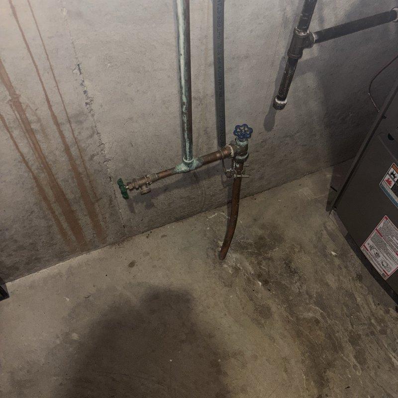 Performed a inspection of the gas tanked water heater, including the supply and distribution piping, shutoff valves, and surrounding ductwork, with no active leaks, frost, or significant damage found. Noted corrosion at a copper branch joint and a drain/hose-bib valve, along with historical mineral staining on the adjacent wall, and recommend monitoring these areas for future maintenance.