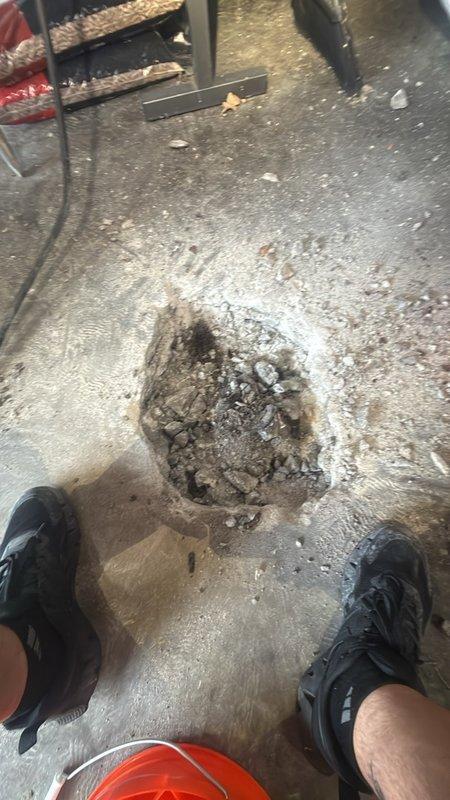 Saw-cut and demolished a section of the garage slab to expose the subgrade for installation of a new floor drain. Excavated the opening, removed concrete debris, and prepared the area for drain body and piping rough-in. Work area was protected during demolition and cleaned of concrete dust and rubble.