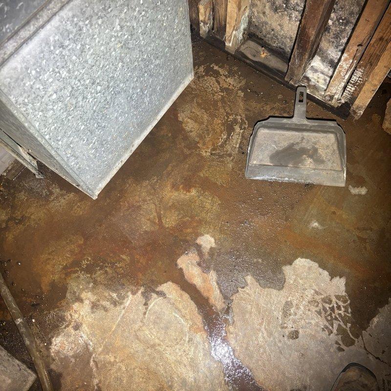 Assessed a water leak at the cast iron drain stack and documented significant pooling, rust staining, and moisture damage on the surrounding concrete floor. Inspected adjacent piping and equipment, including the gas water heater, its flue vent, and corroded supply and gas line fittings, and prepared an estimate for the necessary stack repair.