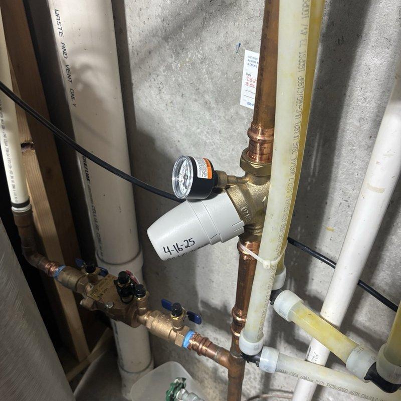 Performed a plumbing inspection of the water supply and treatment components, including copper press-fit piping with brass tee and pressure gauge, a brass backflow preventer assembly with shutoff valves and test cock caps, PEX supply lines, and PVC waste and vent piping. Verified the multi-stage wall-mounted water filtration unit and adjacent RainSoft water softener were properly installed, and found no leaks, corrosion, frost damage, or other deficiencies at the inspected components.