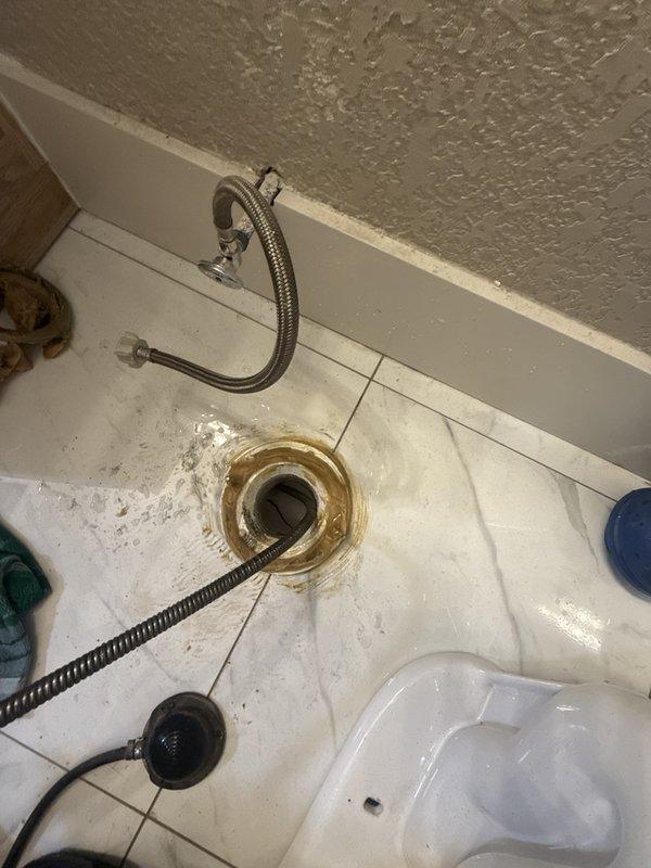 Responded to a main sewer line backup with the bathroom tub and toilet overflowing and multiple fixtures draining slowly. Pulled the toilet to gain direct access to the closet flange and fed a drain-cleaning cable through the opening to clear the blockage in the main line, restoring flow to the affected fixtures. The toilet was then ready to be reset on the flange with the water supply line reconnected.