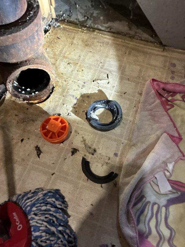 Responded to a callback for a dislodged cleanout cap on the main drain line, which was allowing wastewater to discharge onto the floor whenever fixtures were in use. Inspected the open cleanout and found the cap and its sealing gasket had failed, with the gasket cracked and broken and the threaded fitting heavily corroded. Cleaned up the discharged wastewater and restored the main drain to proper operation, and recommended a camera inspection of the line given the history of recurring clogs.