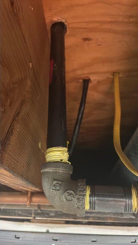 Performed a gas leak inspection and pressure test on the gas piping serving the stove, focusing on the reported area in the basement ceiling near the shut-off valve. Inspected the black iron piping, threaded cast-iron couplings and elbow fittings, and the yellow flexible gas lines, noting surface corrosion on the threaded joints, which were wrapped with thread-seal tape. Gas remained off during the inspection, and the piping was left ready for any needed repair.