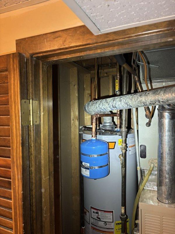 Installed a new 40-gallon gas water heater in the utility closet, with a thermal expansion tank mounted and secured on the supply line to manage pressure fluctuations. Connected the copper supply piping and shutoff valve, then reconnected the gas line and the galvanized flue vent, leaving the unit securely installed and all connections in place.