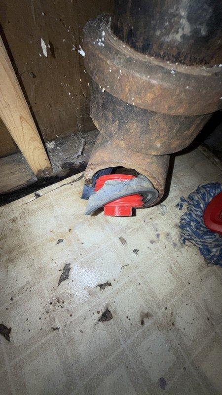 Responded to callback for a dislodged cleanout cap on the main drain that was causing water to discharge when fixtures were in use. Inspection revealed a severely corroded cast iron drain assembly with a cracked fitting that was no longer securing the test cap. Removed the failed component and restored the cleanout closure to stop the leak, and noted the advanced pipe corrosion as a condition warranting further evaluation, including a camera inspection of the recurring drain restriction.