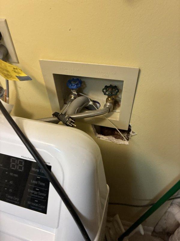 Performed routine maintenance inspection of the tankless water heater and associated plumbing, with no operational issues reported. Inspected the laundry supply valves, braided supply lines, and drain hose, and noted corrosion and mineral deposits on the galvanized tee fitting and tarnished copper piping, along with an unfinished drywall opening below the laundry outlet box, all documented with photographs for the customer's reference.
