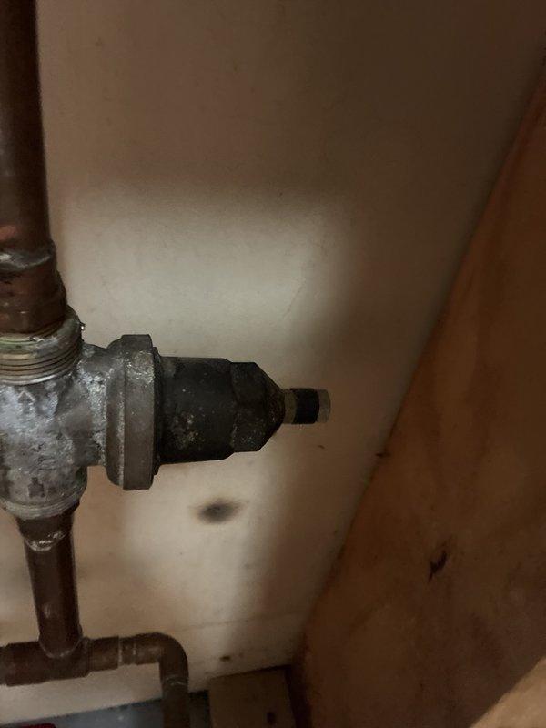 Performed routine maintenance inspection of the tankless water heater and associated plumbing, with no operational issues reported. Inspected the laundry supply valves, braided supply lines, and drain hose, and noted corrosion and mineral deposits on the galvanized tee fitting and tarnished copper piping, along with an unfinished drywall opening below the laundry outlet box, all documented with photographs for the customer's reference.