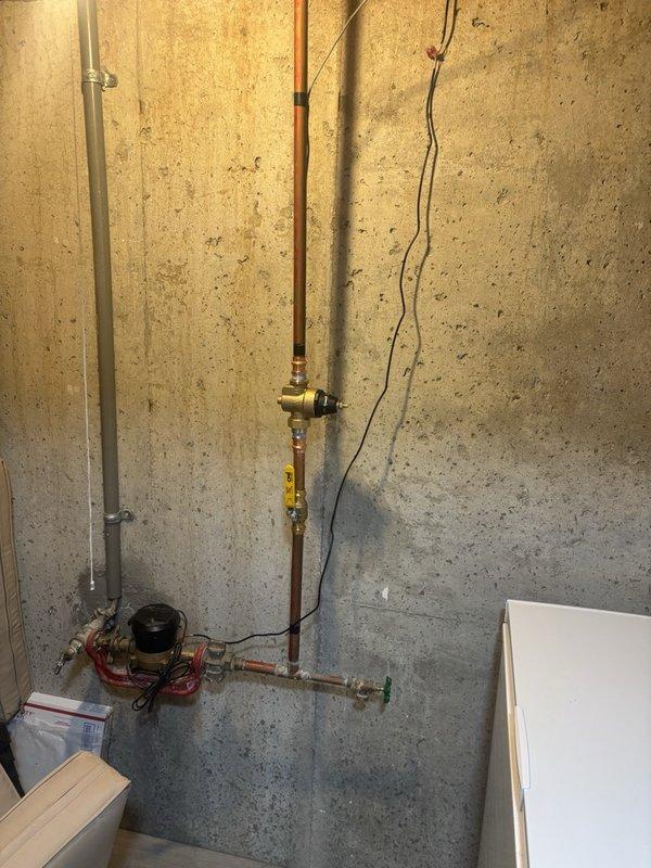 Performed a whole-home plumbing inspection, including a visual assessment of the basement water service entry assembly comprising the copper supply piping, pressure-reducing valve, ball valve, hose bib, and water meter connection. Found no active leaks, corrosion, or visible damage on the inspected piping and valves. Noted the aged main shut-off valve and the second-floor sink faucet flex hoses as known items pending replacement.