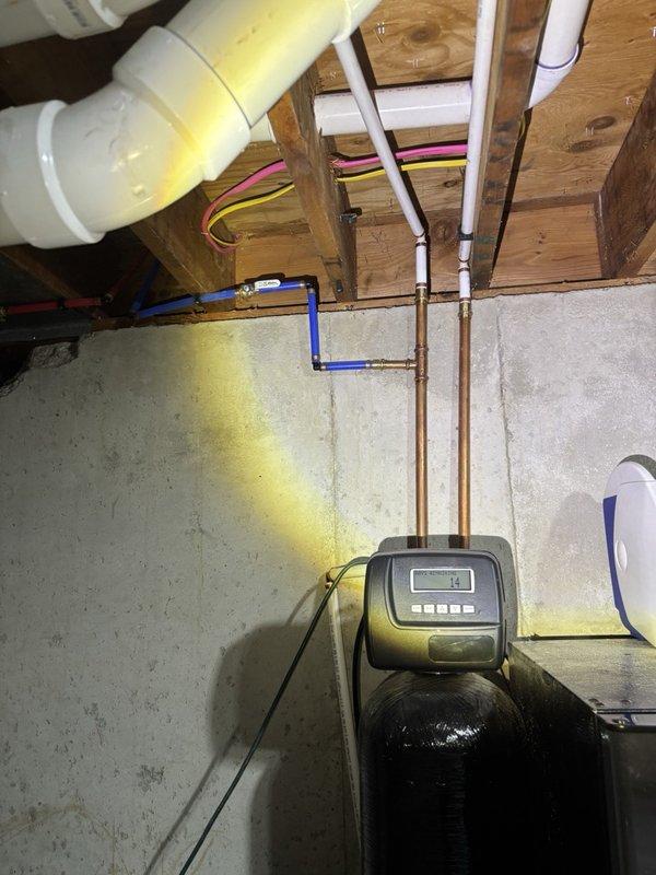 Performed a scheduled plumbing maintenance inspection of the water treatment system, including the water softener with its digital control head, and the associated copper and PEX supply lines with brass fittings. Inspected PVC drain piping, soldered copper joints, and overhead plumbing runs for leaks, corrosion, and fitting integrity, with no active leaks noted; system left in operational condition.