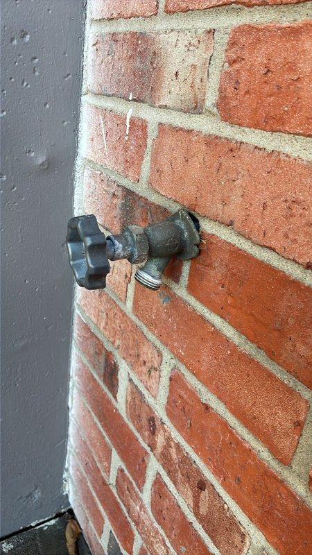 Repaired a leaking exterior hose bib mounted on a brick wall by inspecting the weathered brass spigot and star-shaped handle, then servicing the faucet to stop the leak at the valve and threaded hose connection. Tested the fixture under pressure to confirm the leak was eliminated and operation was smooth. Recommended foam pipe insulation for the exposed outdoor spigot to protect against freezing and further wear.