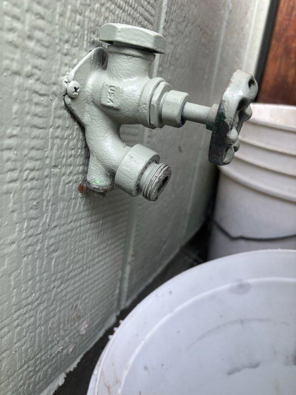 Inspected the reported leak on the copper supply piping and brass valve fitting, and found the copper pipe and its soldered brass connection free of cracks, corrosion, or visible damage. Examined the exterior hose bib, noting worn threads, surface rust, and flaking paint at the wall mount, which is a likely source of moisture. Documented all findings with photographs and recommended repair or replacement of the hose bib to prevent further leaking.