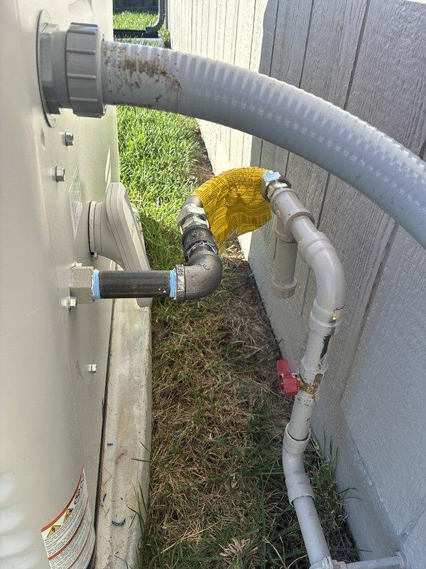 Assessed the gas piping run at the standby generator and prepared an estimate to install the manufacturer-supplied corrugated flexible gas connector between the generator's black iron outlet and the previously installed rigid gas line. The existing configuration includes a black iron nipple and elbow, a shutoff valve on the gray-painted supply pipe, and threaded fittings at both ends of the proposed connector run. Documented the existing piping and fittings with photos to support the installation scope.