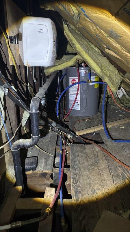 Inspected the attic-mounted water heater and associated piping to assess burst pipe damage and prepare a repair estimate. Evaluated the PEX hot and cold supply lines, copper and brass fittings, and ABS drain with P-trap, noting displaced and damaged fiberglass insulation near the water heater and supply line connections. Documented existing conditions with photographs to support the scope of repair and replacement.