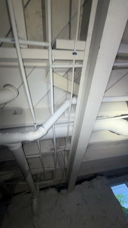 Inspected the toilet tank assembly, including the dual-flush mechanism, flapper valve, fill valve, and float, and confirmed all components were clean and free of cracking or corrosion. Evaluated the accessible drain, waste, and vent piping in the lower-level joist space, verifying that the PVC stack, elbow fittings, and horizontal drain runs were properly supported and secured with no visible leaks or defects.