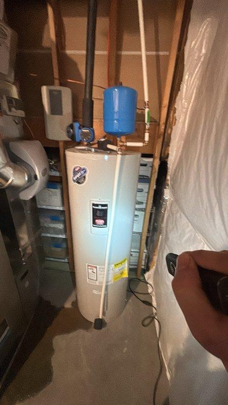 Responded to a leak at the base of an electric tank-style water heater and inspected the unit, including the expansion tank, supply piping, fittings, and surrounding connections, to identify the source of the leak. Performed the necessary repairs to correct the leak, then verified the system was holding pressure with no further moisture at the base of the tank.
