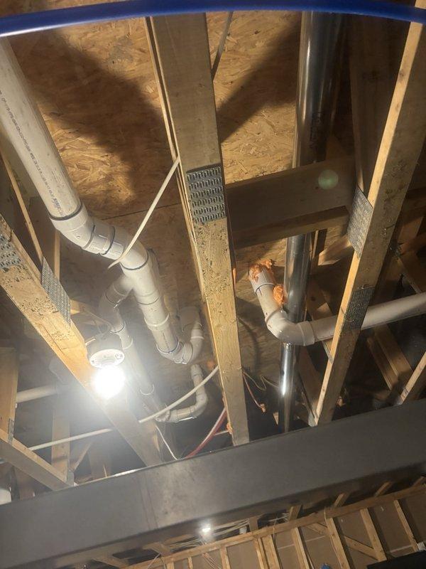 Performed a tankless water heater flush and descaling as part of scheduled plumbing maintenance, and inspected the unit's interior, noting accumulated dust and lint buildup around the freeze protection board that should be cleaned during routine service. Evaluated the home's plumbing and low water pressure concern, including a review of the exposed PVC drain piping in the unfinished ceiling area, and discussed options for a water softener and whole-home water filtration system for a follow-up estimate.