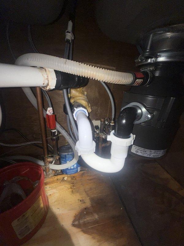 Inspected the detached garbage disposal and found the sink flange severely corroded, with heavy rust buildup around the drain opening, along with water-stained cabinet flooring from prior leaks. Removed the failed flange and mounting assembly, then reinstalled the disposal using a new sink flange and mounting hardware. Reconnected the discharge elbow and P-trap with slip-nut fittings, verified secure connections, and tested the unit for proper operation with no leaks.