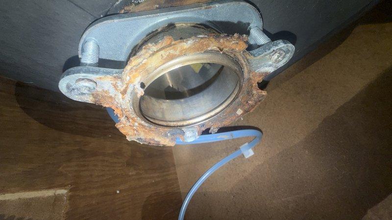 Inspected the detached garbage disposal and found the sink flange severely corroded, with heavy rust buildup around the drain opening, along with water-stained cabinet flooring from prior leaks. Removed the failed flange and mounting assembly, then reinstalled the disposal using a new sink flange and mounting hardware. Reconnected the discharge elbow and P-trap with slip-nut fittings, verified secure connections, and tested the unit for proper operation with no leaks.