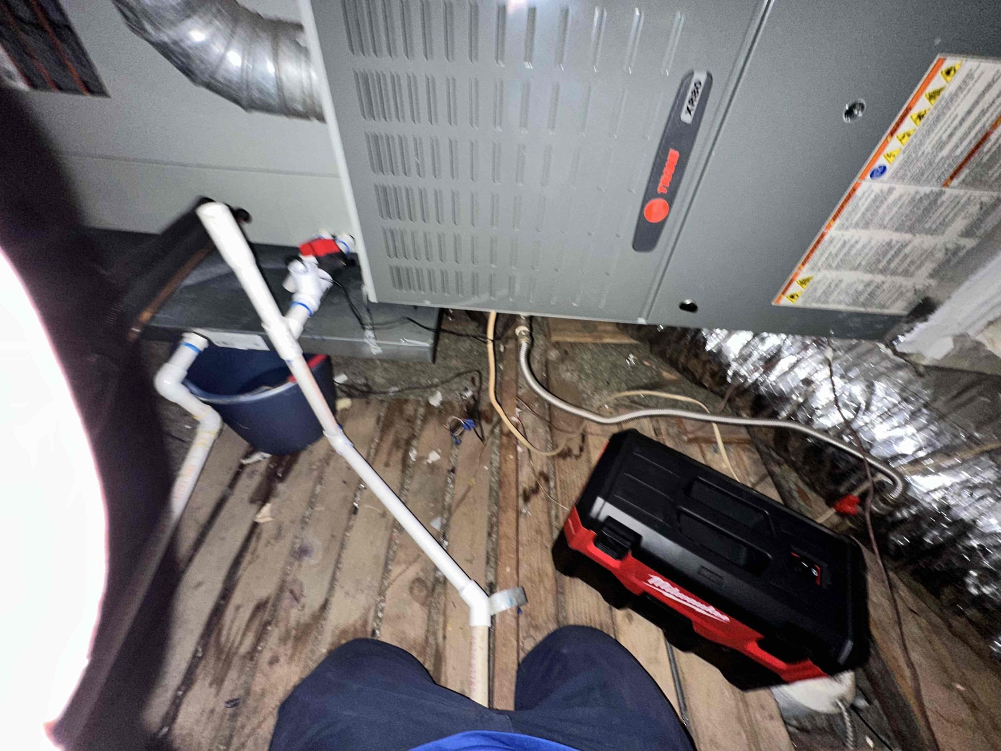 Upon arrival, I found that the primary drain had a slow drain. The primary was empty. I checked for back pressure with my mouth and found it to be clogged. The water was going in to the emergency pan. The water stain came from the keeper screw ,holding the emergency drain to the pan, not being tight. I tightened the screw and used a shop vac and pressure to clear the drain. Also, I used the accumulated water from the leaking pan to flush the drain and followed it with some drain cleaner. It was half a bucket of water. The customer and I spoke about redoing the drain under the sink to allow more access and adding a wet switch to the emergency pan. Customer declined further repairs. 
