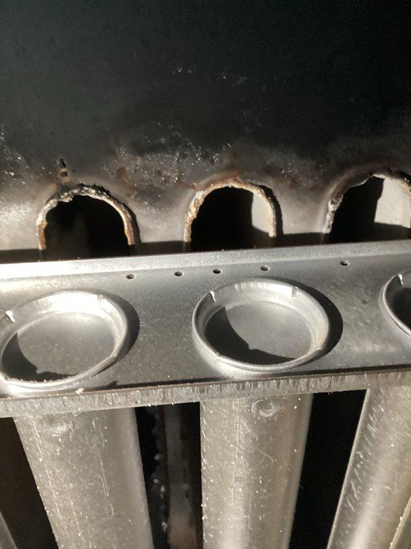 Responded to service call for commercial garage heater not producing heat. Upon inspection, identified cracked heat exchanger with significant corrosion and deterioration around burner ports. Unit was red-tagged as unsafe for operation and requires complete replacement.
