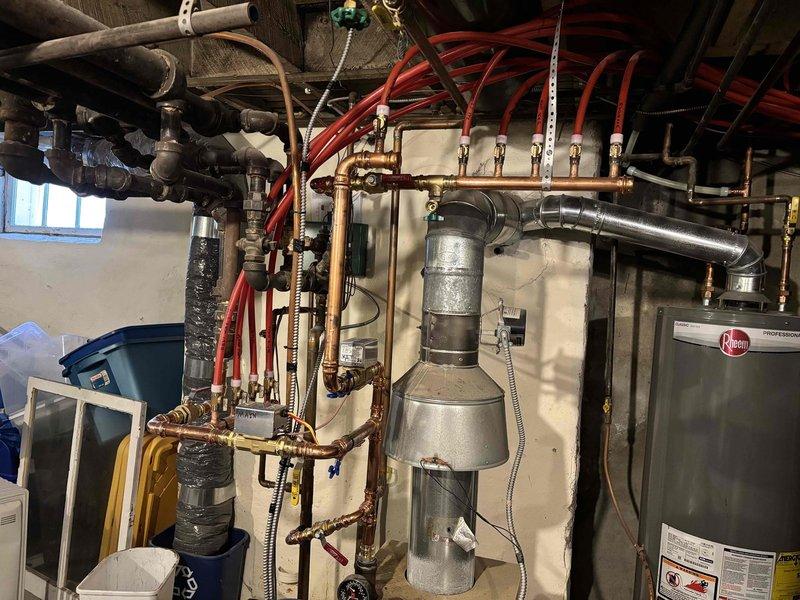 Performed Fall tune-up maintenance on customer's Rheem heating system including inspection of one boiler and one gas-fired pump. Serviced basement utility area containing extensive copper piping network and ventilation ductwork. System appears to be functioning properly with no issues identified.