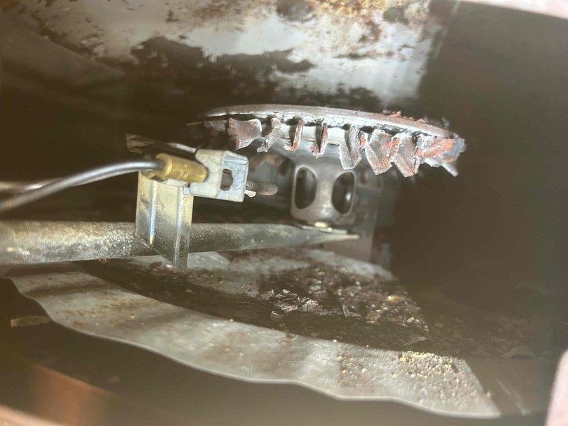 Responded to service call for non-functioning in-floor heating system, initially referred by Nick Flann. Inspection revealed water heater in unsafe condition with significant corrosion on burner assembly and visible rust throughout the unit. Observed active leakage from manifold connection and extensive deterioration of mechanical components that prevented proper system operation.