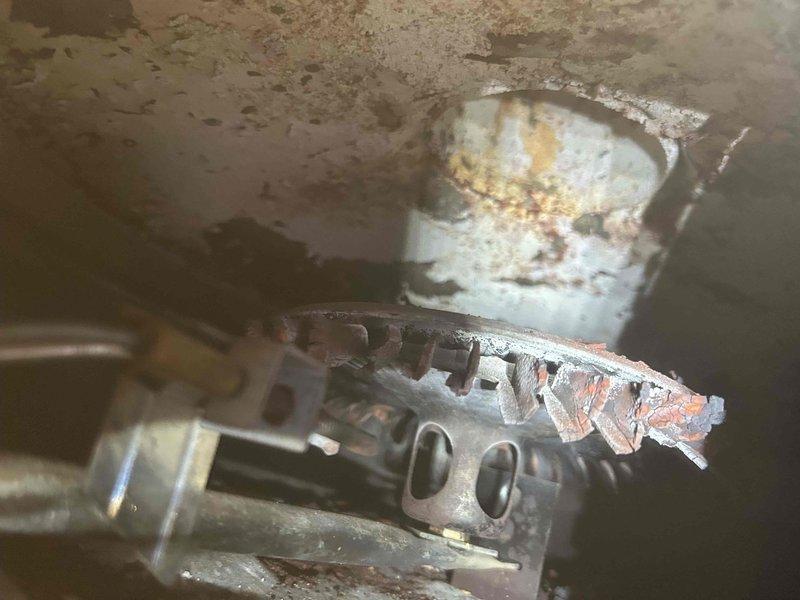 Responded to service call for non-functioning in-floor heating system, initially referred by Nick Flann. Inspection revealed water heater in unsafe condition with significant corrosion on burner assembly and visible rust throughout the unit. Observed active leakage from manifold connection and extensive deterioration of mechanical components that prevented proper system operation.