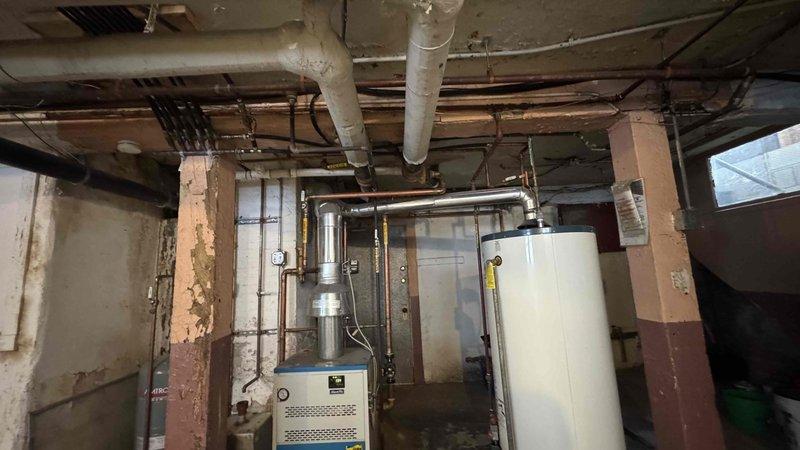 Conducted inspection of kitchen faucet with low hot water pressure issue. Upon assessment, determined problem was not with the faucet (previously replaced by another technician) but traced to restrictions in the hot water supply line. Inspected basement mechanical room containing boiler system and water heater, examined exposed plumbing infrastructure and identified mineral buildup in hot water supply pipes contributing to pressure loss. Cleared obstruction and restored proper hot water pressure to kitchen faucet.