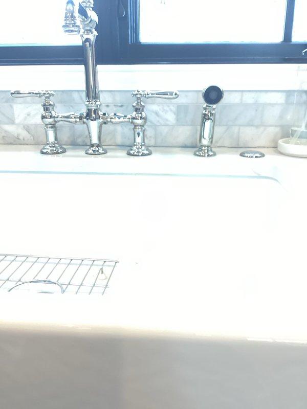 Performed warranty service on kitchen faucet that presented with multiple issues: dripping, sprayer hose hanging up, loose sprayer hose, and loose cold side handle. Replaced cartridges, repositioned sprayer hose behind supply lines to prevent hanging, and tightened both the sprayer hose and cold side mounting bracket under sink to restore proper functionality.